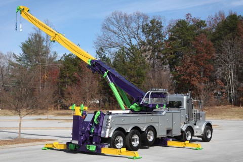 silver purple and yellow century 1075s rotator with boom and outriggers extended in a parking lot