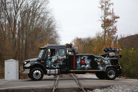 side photo of a black vulcan v-30 on a freightliner m2 chassis crossing railroad tracks