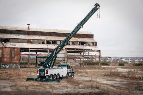 white and green century m100 with boom and outriggers fully extended at an old factory