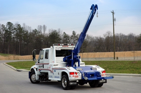 white and blue century 602 wrecker with the boom extended
