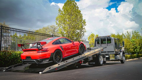 orange porsche carrera gt2rs being loaded on a century 12 series lcg carrier with right approach option