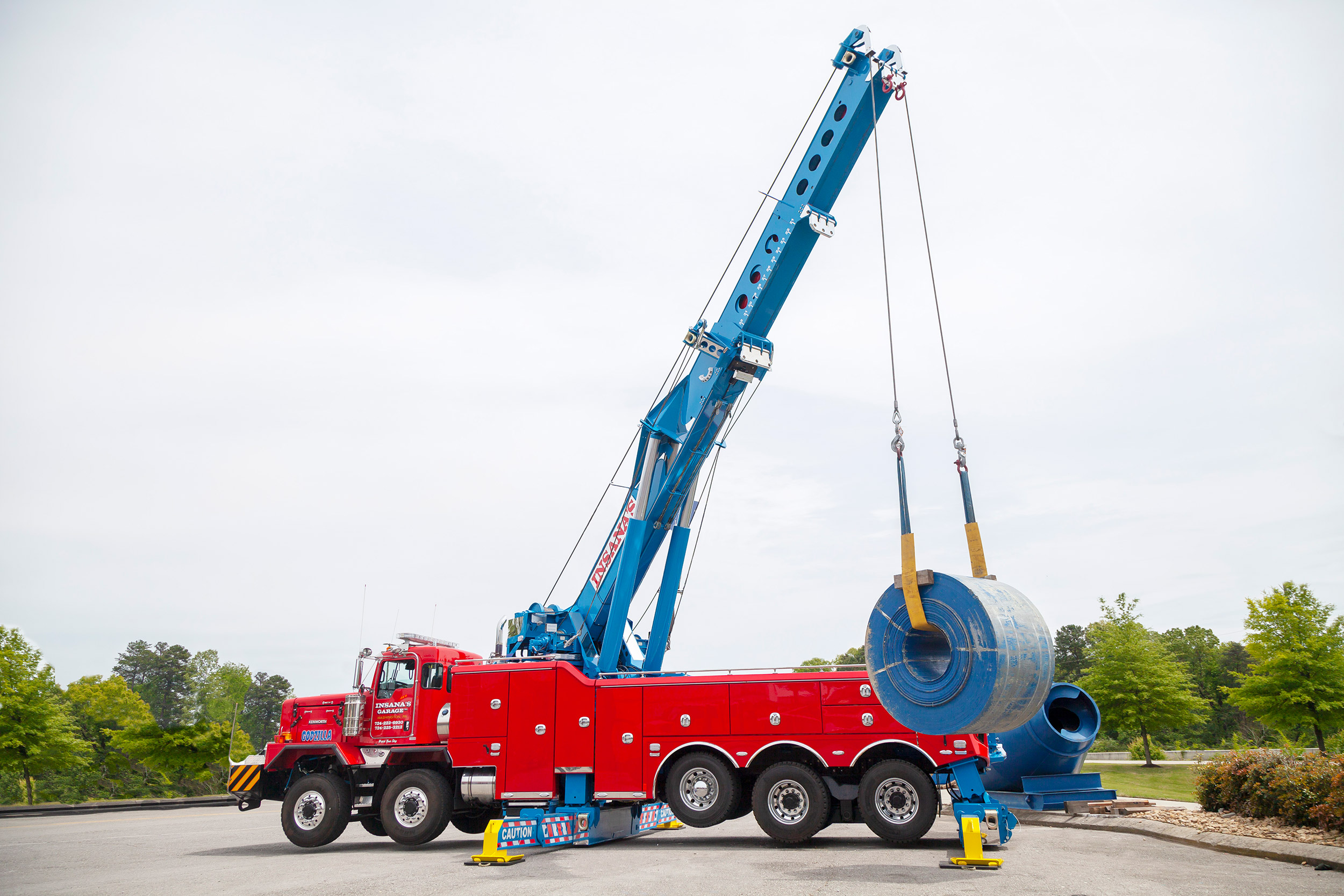 Red Century M100 on a Kenworth C500 chassis lifting a steel coil