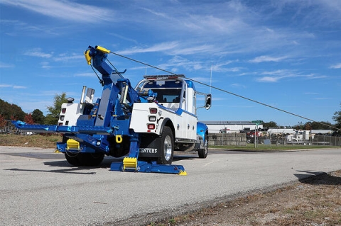 Image showing a 3212 medium-duty wrecker conducting a hard side pull recovery while using the extendable rear jacklegs to provide added stability for the wrecker.