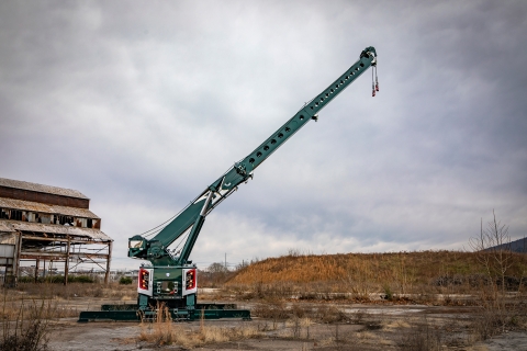 rear of a white and green century m100 rotator on a kenworth c500 chassis with boom and outriggers extended