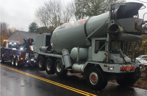 Image show a Century®️ 9055 wrecker towing a fully loaded concrete mixer from the rear.