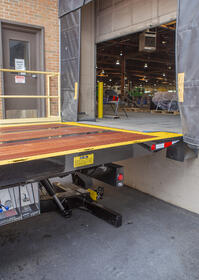 Image showing a Century 30-Series Industrial Carrier at a warehouse loading dock using the dock stabilizer option to stabilize the deck and elevate the hight of the deck to better align with the different heights of loading docks.
