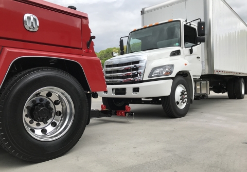 In this picture a Century medium-duty wrecker using medium-duty forks is towing a disabled box truck.