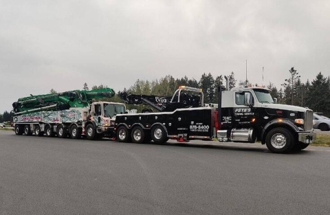 This image shows a Century®️ 1150 Rotator Towing a concrete pump truck on knee-boom style underlift. This demonstrates the versatility of the knee-boom underlift with its ability for reach and height when towing.