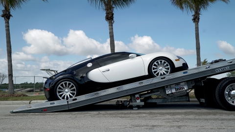 black and white bugatti veyron being loaded on a gray century 12 series lcg with right approach option