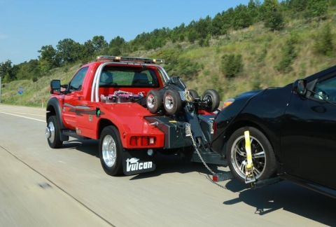 This images show a Miller Industries light-duty autoloader traveling down the interstate towing a passenger vehicle.