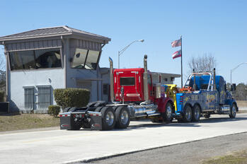 Image shows a Century 5130 Integrated Wrecker from Miller Industries driving through and clearing the scales while towing a casualty without a counterweight.