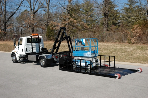 titan c series with the roll off bed on the ground loaded with a scissor lift