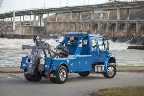 blue vulcan v-30 on a freightliner m2 chassis in front of a river dam