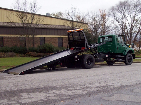 Rear view of a Century military carrier in army green with the bed extended.