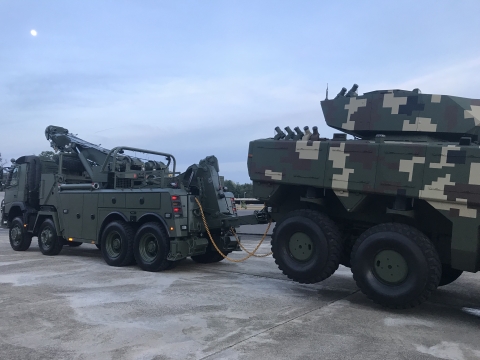 A military Century 1140 towing a military armored combat vehicle from the rear