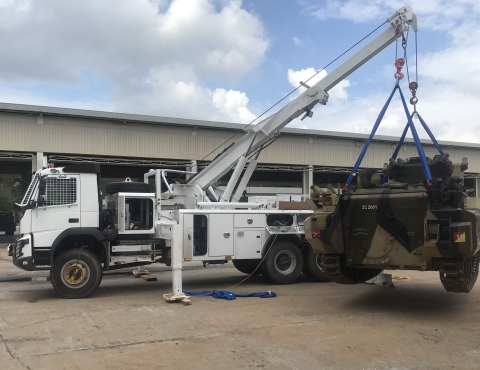 A Century 1135 lifting and rotating a heavy armored small military tank 30 degrees off the tailboard and around the rear corner of the wrecker.