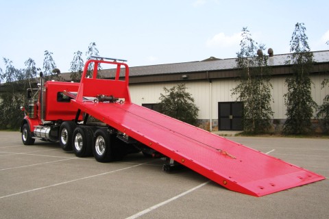 red kenworth w900 chassis with a century 40 series industrial carrier bed tilted back
